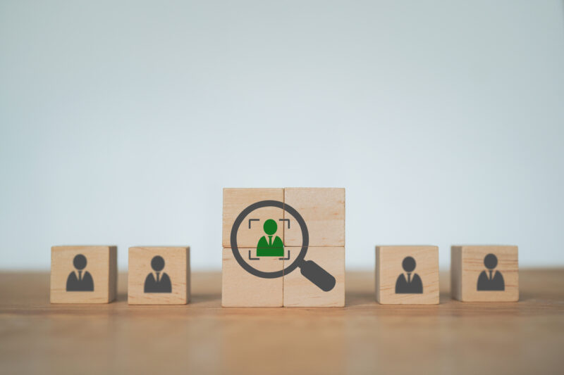 green businessman and crop inside magnifying glass icon with blur others for leadership, smart employee, outstanding person concept