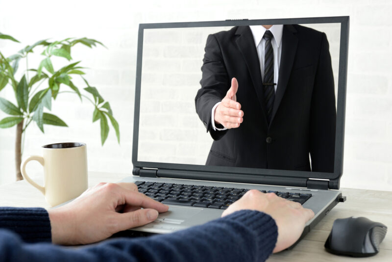 Man using pc with screen of business man trying to shake hands