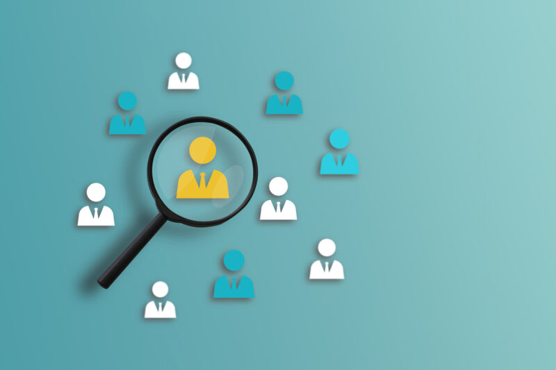 HRM or Human Resource Management, Magnifier glass focus on the yellow human icon for a select employee. Recruitment leadership and customer target group concept.