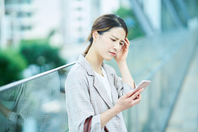 A young woman looking at a smartphone screen with a troubled expression