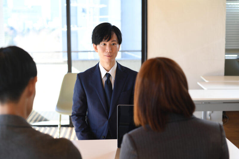 Young Asian male and female interviewer interviewing a young Asian man in a suit