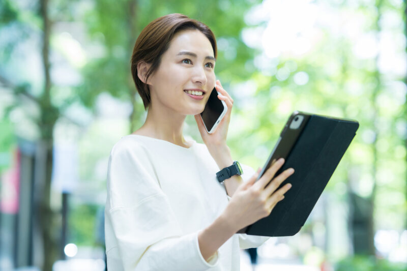 A young woman talking on a smartphone while operating a tablet